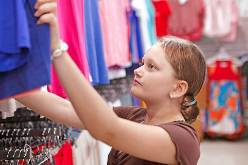 Young girl in the clothing store looking for some clothes