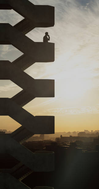 Open stairs at the edge of the frame, on one of the stairwells at a high altitude there is a man admiring the city sunset and talking on the phone