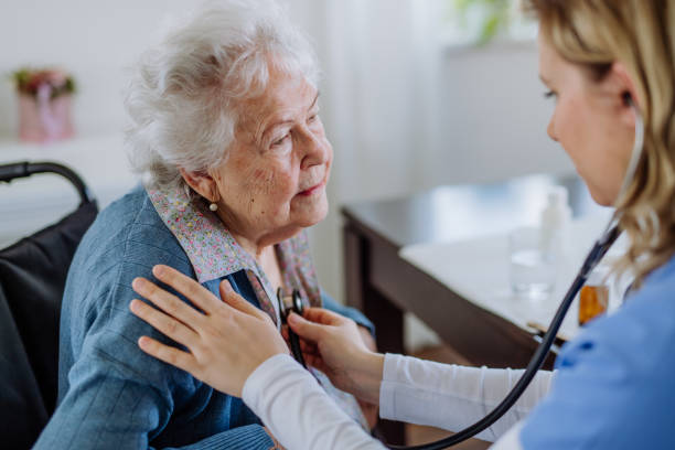 istock Nurse examining senior patient with stethoscope at her home. 1482561115