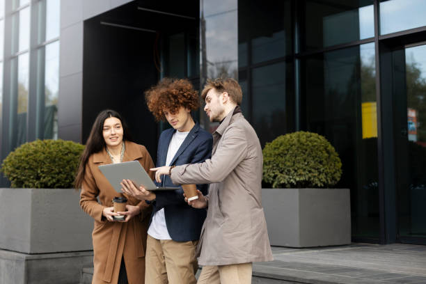 istock Beautiful, young team of workers working outdoors, using laptop. Young people near modern office 1482562783