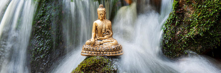 Buddha sculpture sitting in flowing water cascade