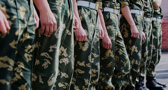 Russian military detachment of border guards stands on the street. Hands and boots close-up.