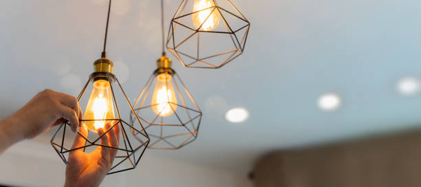 istock An electrician is installing spotlights on the ceiling. Handyman choosing between energy save and cheap incandescent lamp while changing light. 1482566059