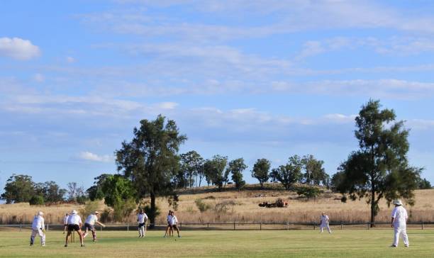 uomini australiani che giocano a cricket nel parco locale - sport of cricket village cricket player english culture foto e immagini stock