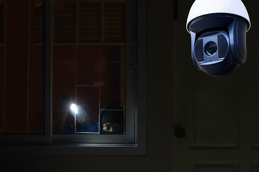 CCTV Camera Showing A Burglar Stealing Things In The House. Thief wearing black suit with balaclava and glove being caught by CCTV, surveillance camera during sneak into a house at night