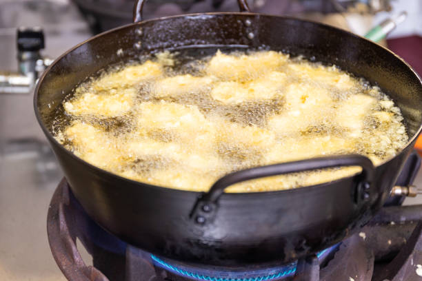 Pieces of Japanese Fu - Wheat Gluten tempura frying in a wok full of oil.