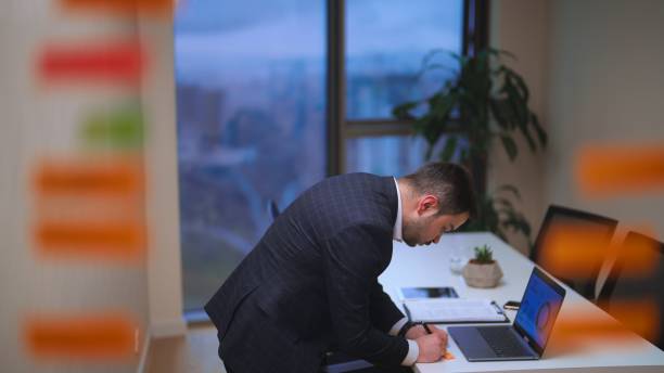 istock Young businessman sticks post-its on glass and brainstorming in office 1482572200