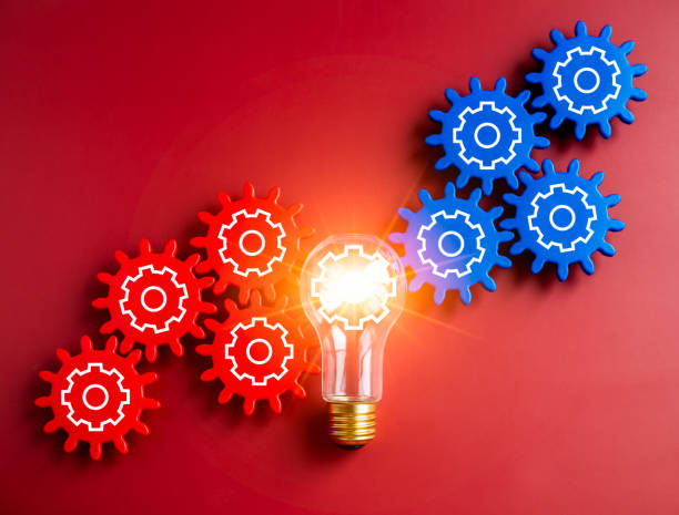 istock Glowing light bulb connected between blue and red gear wheels on red background. Business strategy, management and solution, human research, connection, teamwork and creative idea concepts. 1482582651