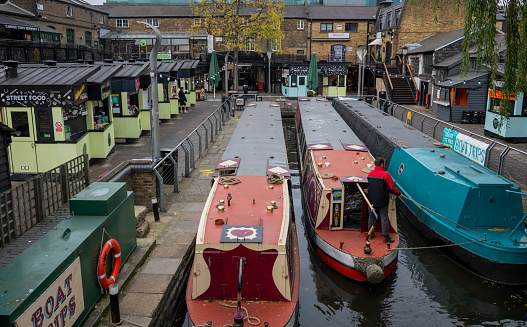 Under the bridge on Regent's Canal, far away you can see Traditional narrowboats and houseboats moored.