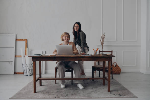 istock Two happy young businesswomen using laptop while working together at the creative office 1482589048