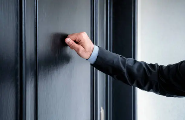 Close up of young man knocking on the door with copy space