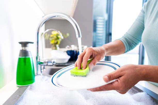 istock Woman washing dishes with a sponge 1482591351