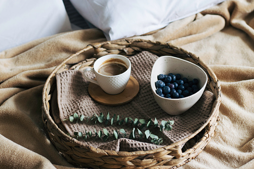 breakfast with coffee and cookies in bed with gray blanket.