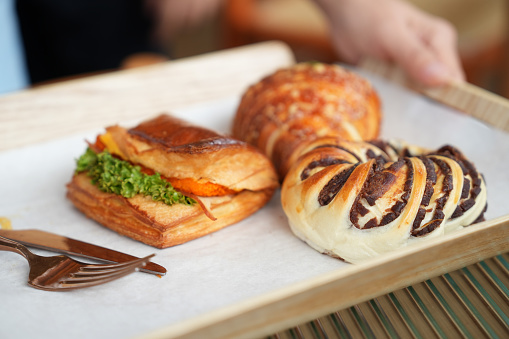 Cropped shot of a woman holding a serving tray with assortment of pastries and bread buns