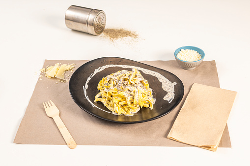 Nice pasta dish with delicious tagliatelle tartufata recipe with grated cheese and parmesan flakes on a white table.