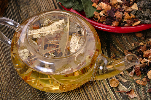 Healthy hot herbal tea with sage in glass kettle.