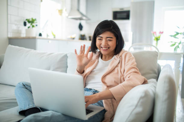 istock Young woman using a laptop while sitting on a couch in a living room 1482598440