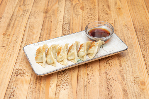 Popular plate of Asian dumplings fried grilled gyozas with soy sauce to dip on a beautiful white plate
