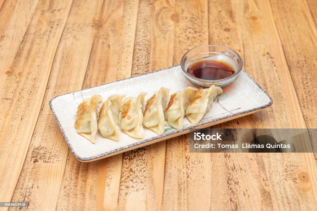 Popular plate of Asian dumplings fried grilled gyozas Popular plate of Asian dumplings fried grilled gyozas with soy sauce to dip on a beautiful white plate Asian Food Stock Photo