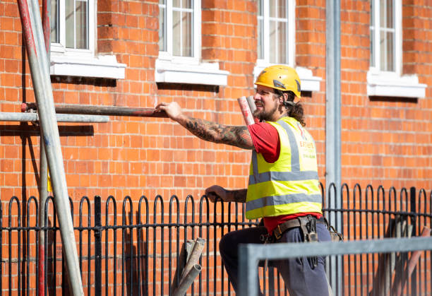 construction workers putting up scaffolding around a building. - couplers imagens e fotografias de stock