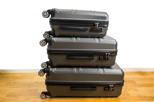 Close-up view of three suitcases on wheels of different sizes on parquet floor in room. Sweden.
