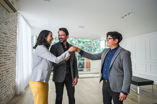 Real estate agent giving new house key to a couple