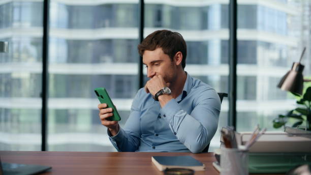 istock Laughing boss reading smartphone message office. Man smiling looking cellphone 1482609914