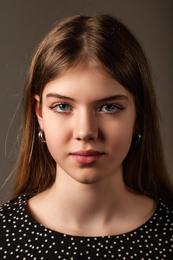 Closeup portrait of pretty jewish teenage girl with long hair and blue eyes, looking at camera. Face of serious jew teen lady close up, studio shot. Youth positive emotion concept. Copy ad text space