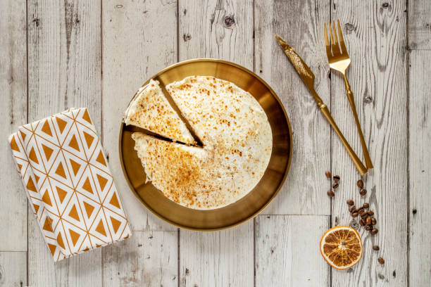 Top view image of carrot cake on plate and golden cutlery with coffee beans, dried orange,
