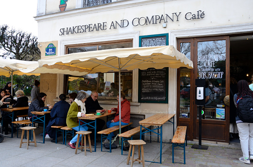 Paris, France - March 17, 2023: People at cafe terrace of iconic bookshop Shakespeare and Company in the Latin Quarter in Paris, France.