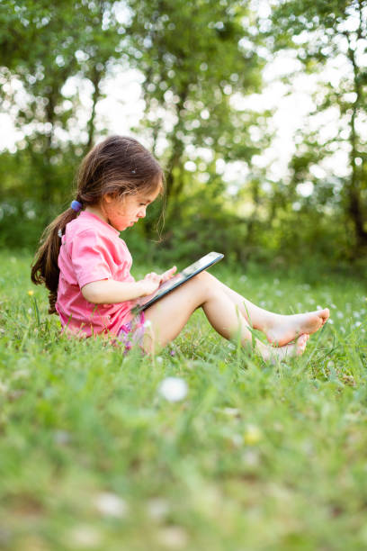 istock Little girl playing on tablet in nature 1482627562