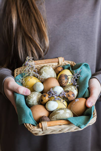 istock Basket in female hands with eggs dyed with natural eco-friendly dyes for easter vertical view 1482628032