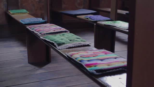 colorful cushions on very old brown church pews