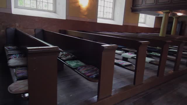 rows of church pews with colorful cushions and windows