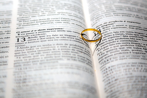 A golden wedding ring placed on top of a stack of open book pages, symbolizing the binding nature of marriage