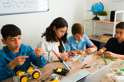 Group of young teens at school building robots and electronic circuits while building a prototype together