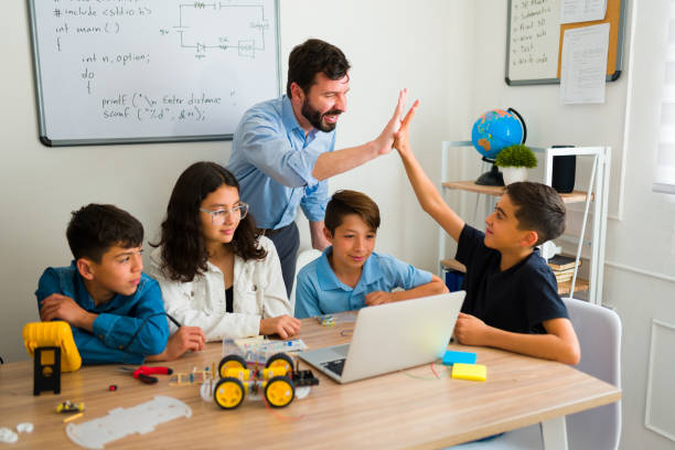 istock Cheerful robotics instructor doing a high five with a teen boy at school 1482634421