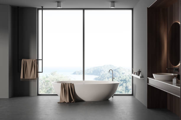 istock Grey bathroom interior with sink and accessories, tub near panoramic window 1482636239