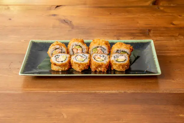 serving of crunchy uramaki sushi roll with flambéed salmon, nori seaweed, avocado, Japanese vinegar and cooked rice