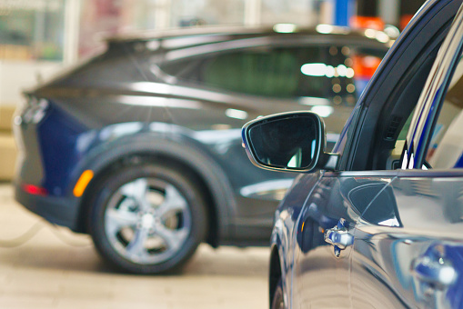 New car in dealer showroom. blurred background. Focus is on the handle of the left car