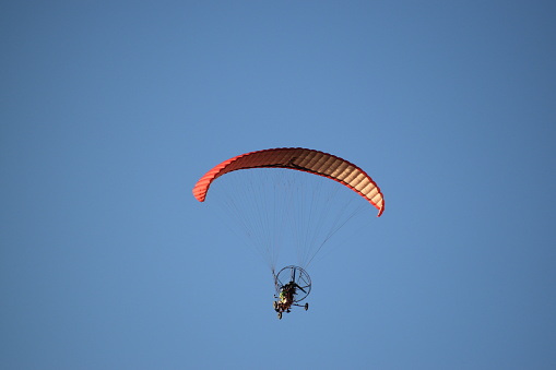 Paraglider against mountains and meadows, Monte Baldo, Lake Garda, Italy.
