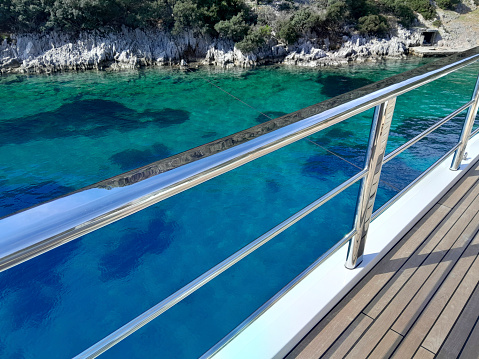 Safety railing and wooden deck of cruise ship. Vessel sailing on the Caribbean Sea. Sunset time. Blue sky and some clouds. Space for copy. Horizontal lines.