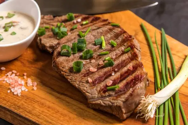 Rump steak on a wooden board with mushroom sauce. Quality beef. Barbecue season. Medium grilled steak.