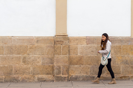 Sucre, Bolivia, April 1 2023 : Bolivian woman walkin,g along a typical colonial white facade.