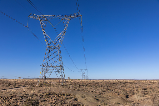 High voltage electricity transmission pylons going into the distance in the Karoo area of South Africa