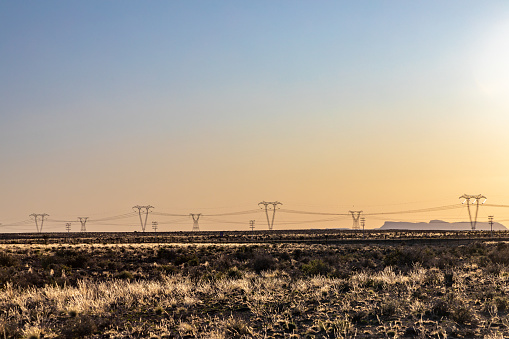 High-voltage power lines at sunset, high voltage electric transmission towers in the Karoo area of South Africa.