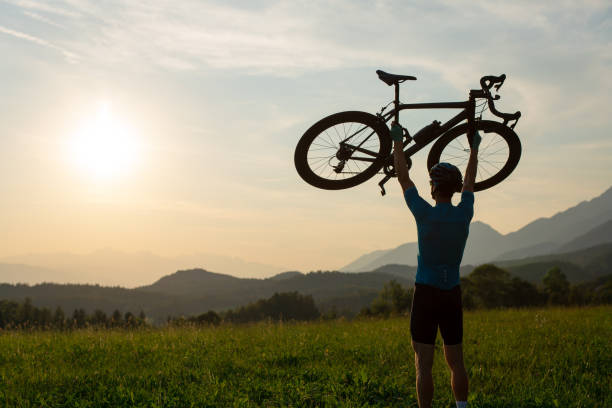 istock Cyclist rising a bicycle above his head and looking at sunset 1482650248