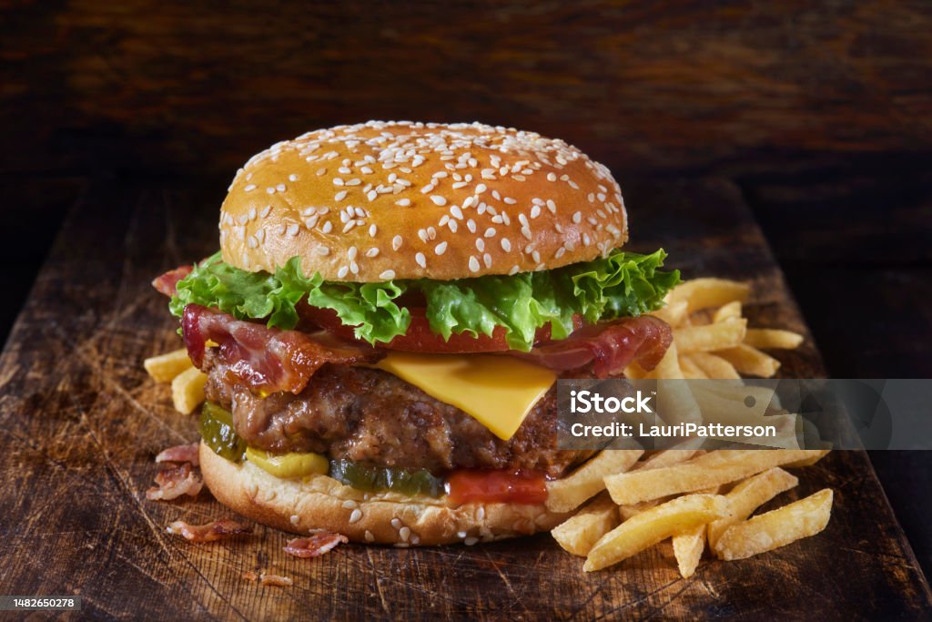 Juicy Ground PORK and Bacon Cheeseburger with Fries Grilled Juicy Ground PORK and Bacon Cheeseburger with Lettuce, Tomato, Pickles, Ketchup, Mustard and Fries Burger Stock Photo