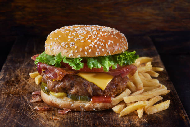 juicy ground pork and bacon cheeseburger with fries - hambúrguer imagens e fotografias de stock