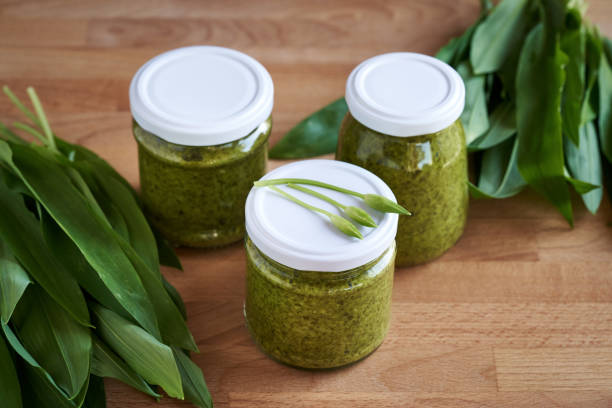 Canned wild garlic pesto with fresh ramson leaves and buds
